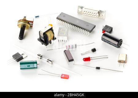 Différentes pièces ou composants électroniques sur fond blanc avec résistances, condensateurs, puces à diodes et ci, mise au point sélective Banque D'Images