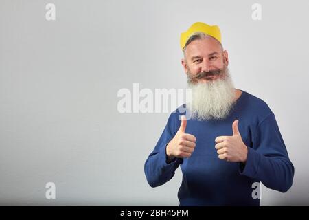 Le portrait d'un homme barbu mûr à poil gris montre deux pouces sur fond gris, foyer sélectif Banque D'Images