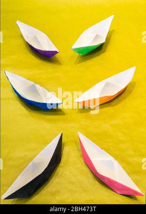 Bateaux en papier peint couleur eau colorée sur surface jaune disposés symétriquement Banque D'Images