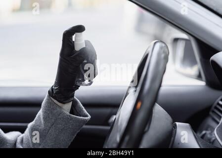 Mains féminines dans des gants de protection en caoutchouc désinfectant l'intérieur de la voiture pour la protection contre la contagion du virus. Nettoyage de la direction de voiture, pulvérisation de désinfectant liq Banque D'Images