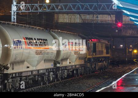 EWS Livery DB Cargo rail UK classe 66 locomotive 66103 station de Carlisle humide avec un train de fret de chars de ciment château la nuit avec un signal d'arrêt rouge Banque D'Images