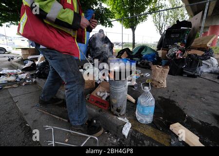 Portland, États-Unis. 23 avril 2020. Un sans-abri qui ne voulait pas être identifié prépare à cuisiner de la nourriture dans son camp de l'autre côté de la clôture à partir d'un abri temporaire logé dans un parking sur Southwest Water Avenue à Portland, Oregon, le 23 avril 2020. C'est le premier des trois refuges extérieurs mis en place par les responsables de la ville pour offrir une alternative plus sûre à être dans les rues pendant la pandémie. (Photo d'Alex Milan Tracy/Sipa USA) crédit: SIPA USA/Alay Live News Banque D'Images