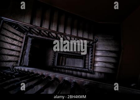 Grand angle au-dessus de la vue en bas de la vieille spirale d'escalier vintage sinueuse à Lviv, Ukraine, Europe avec personne architecture sombre bas-clé abstrait modèle Banque D'Images