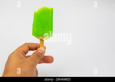 Main de l'homme tenant la crème glacée Popsicle citron goût sur fond blanc. Banque D'Images