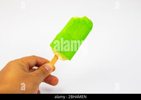 Main de l'homme tenant la crème glacée Popsicle citron goût sur fond blanc. Banque D'Images