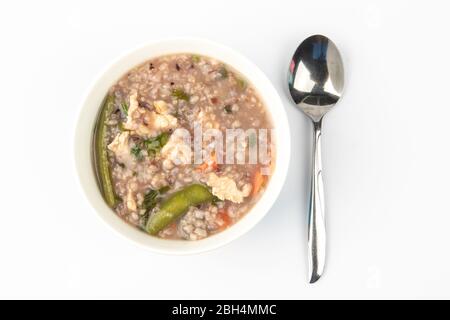 Délicieux porridge de riz brun maison avec peu de tranches de poulet, de carottes et de légumes isolés sur fond blanc. Banque D'Images