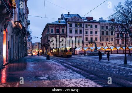 Lviv, Ukraine - 28 décembre 2019: Place du marché de la vieille ville à Lvov avec éclairage de Noël d'hiver et vider rynok la nuit avec la neige et le troll de tram Banque D'Images