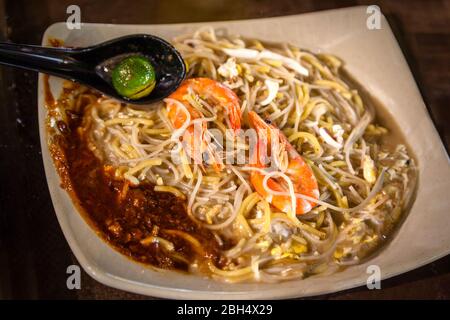 Cuisine de Singapour fruits de mer Hokkien Mee avec des crevettes géantes, calmar, porc et œufs frits avec des nouilles jaunes et vermicelles dans le bouillon de fruits de mer. Service Banque D'Images