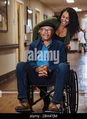 Femme souriante poussant l'homme en fauteuil roulant Banque D'Images