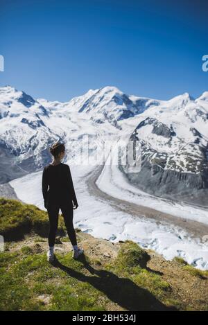 Femme debout sur l'herbe par le glacier Gorner en Valais, Suisse Banque D'Images