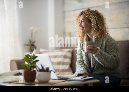 Femme souriante tenant un verre sur un ordinateur portable Banque D'Images