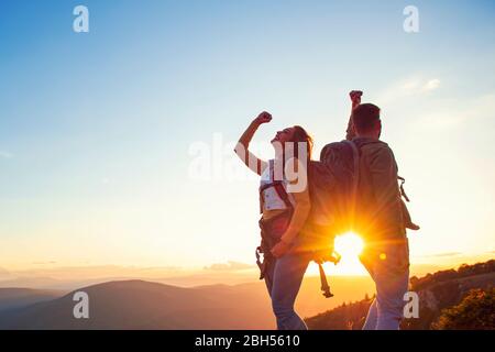 Couple sur un sommet d'une montagne secouant les mains levées Banque D'Images