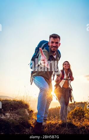 Les gens qui s'aident à monter une montagne au lever du soleil. Banque D'Images