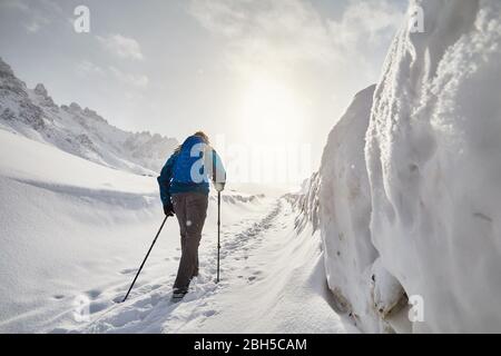 Sac à dos bleu touristique avec la marche sur la route de la neige dans les montagnes de neige au Banque D'Images