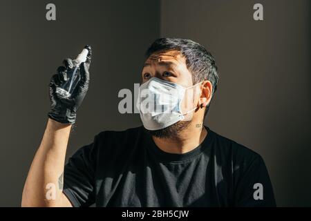 Coronavirus. Homme portant un masque de protection médicale et un gant en caoutchouc noir vaporisant de l'aseptisant en interne pour éviter le Coronavirus, Covid-19, fl Banque D'Images