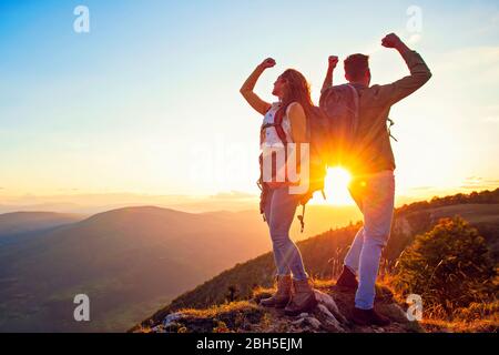 Couple sur un sommet d'une montagne secouant les mains levées Banque D'Images