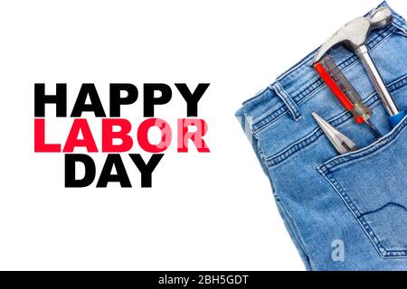 TEXTE HEUREUX DE LA JOURNÉE DU TRAVAIL avec jeans, tournevis, marteau et pinces sur fond blanc. Concept de la journée du travail Banque D'Images