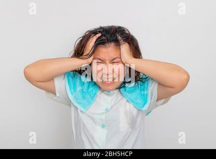 La fille asiatique ont des maux de tête et hurlant de douleur dans son pyjama bleu robe bleu avec une petite serviette sur son cou.