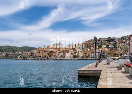 Porto Santo Stefano, Grosseto, Toscane, Italie, avril 2018: Quai sur le front de mer dans le village de Porto Santo Stefano dans une journée ensoleillée avec beau ciel nuageux. Banque D'Images