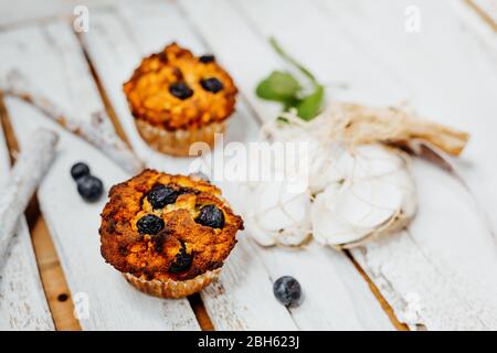 Muffins sains avec farine de coco et bleuets sur une assiette en bois clair décorée de menthe et de coquillages Banque D'Images