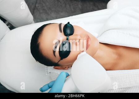 Une femme présente des lunettes de sécurité reçoit une procédure d'épilation au laser. Retrait de la moustache Banque D'Images