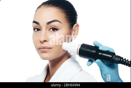 médecin faisant une thérapie par ondes acoustiques à une femme. Rajeunissement de la peau avec des ondes acoustiques. Portrait des femmes sur un fond blanc Banque D'Images