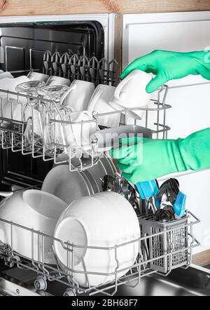 La main féminine courte permet de retirer les plats propres du lave-vaisselle. Vaisselle parfaitement lavée. Lave-vaisselle intégré Banque D'Images