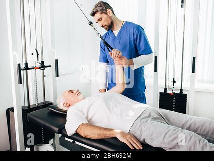 traitement de la douleur dans l'articulation de l'épaule avec kinésithéapy. la prise de rétablissement conjoint , kinésithérapeute traite un patient senior Banque D'Images