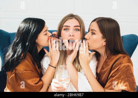 les femmes de chambre mariées vêtues de peignoirs en satin lui donnent des nouvelles choquantes dans son oreille. Week-end de Bachelorette Banque D'Images