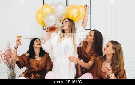 amies portant des robes de satin célébrant la fête de la poule . mariée buvant de l'alcool et s'amuser avec ses amis. Seulement la fête des femmes Banque D'Images