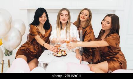 Heure de la fête du pyjama. De belles amies charmantes célébrant la fête des poules, buvant de l'alcool et riant à l'hôtel Banque D'Images