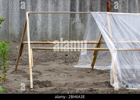 Étape de la construction d'une serre de lamelles en bois et polyéthylène dans le jardin. Banque D'Images