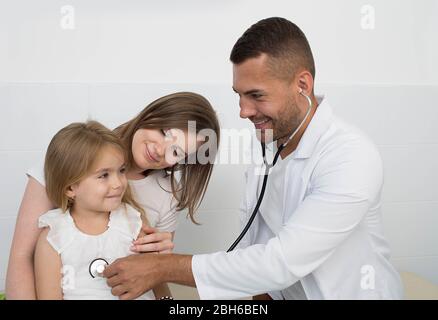 Médecin pédiatrie positive tout en travaillant avec un enfant. mère avec un enfant examiné par un pédiatre Banque D'Images