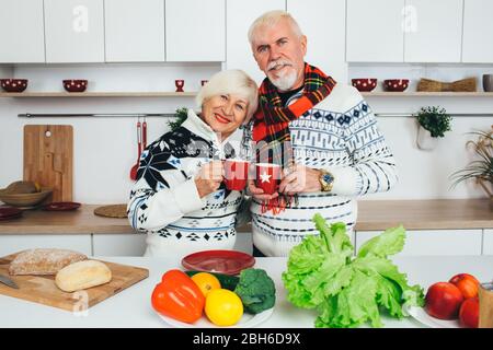 Personnes âgées couple heureux boire du thé debout à la maison dans la cuisine, les personnes âgées passent du temps ensemble à la maison. Banque D'Images