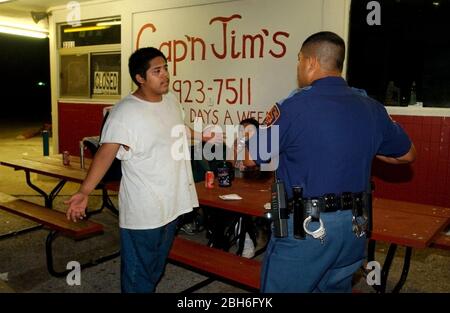 San Antonio, Texas, États-Unis, août 2003 : un policier interroge un adolescent qui se tient devant une remorque fermée tard pendant une nuit de service. ©Bob Daemmrich Banque D'Images