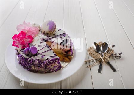 Cheesecake aux bleuets maison décoré de fleurs et de macaron sur fond de table blanc en bois. Vue de dessus. Banque D'Images