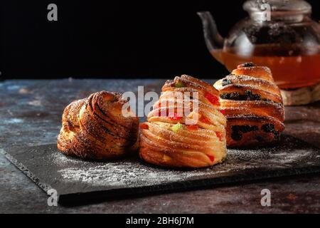 Kraffins aux raisins secs, fruits confits et graines de pavot, arrosés de sucre en poudre. Banque D'Images