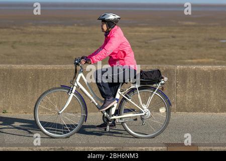 Southport, Merseyside. Météo britannique. 24 avril 2020. Une autre journée ensoleillée de printemps dans le complexe, alors que les habitants de la région prennent des exercices légers. Femme conduite White Pendleton Somerby Electric Bike sur la promenade du front de mer. Crédit: MediaWorldImages/AlamyLiveNews Banque D'Images