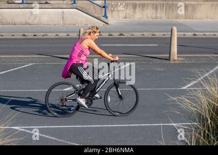 Southport, Merseyside. Météo britannique. 24 avril 2020. Une autre journée ensoleillée de printemps dans le complexe, alors que les habitants de la région prennent des exercices légers. Femme à cheval Muddyrenard femme vélo sur la promenade du front de mer. Crédit: MediaWorldImages/AlamyLiveNews Banque D'Images