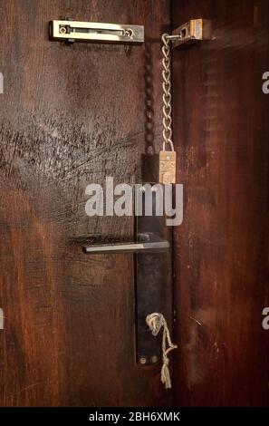 Ancienne porte en bois avec serrure à chaîne, clavette dans un trou de serrure et poignée de bouton de porte. Concept de sécurité vintage Banque D'Images