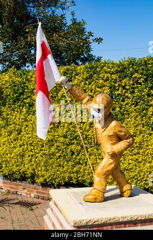 Statue en bois sculpté de « Clockpelters » portant un masque médical lors de la pandémie de Covid-19, le jour de Saint-Georges avec un drapeau anglais. Super gonerby, Grantha Banque D'Images