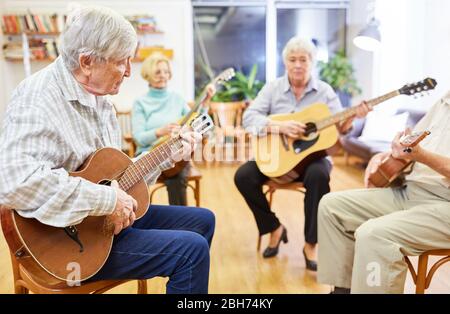 Groupe d'aînés sur des cours de guitare dans leur temps libre ou comme ergothérapie Banque D'Images