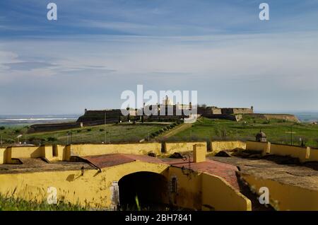 Forteresse de Santa Luzia au sommet d'une petite colline vue de derrière les murs défensifs jaunes de la ville d'Elvas. Ciel bleu nuageux. Alentejo, Portugal. Banque D'Images