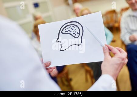 Le médecin féminin avec un dessin du cerveau donne une conférence sur la démence et la mémoire Banque D'Images