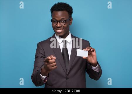 Jeune africain américain homme en costume tenant la carte de crédit pointant sur vous. Banque D'Images