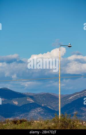 Un seul mouette prend un peu de repos sur la sale rue lumière, regardant à gauche. Ciel bleu impressionnant nuageux et journée d'hiver ensoleillée au lac de Vistaïda, Porto Lagos, région de Xanthi, Grèce du Nord Banque D'Images