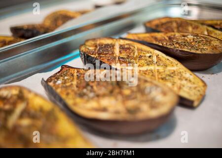 Rangées de moitiés d'aubergines en morceaux sur du papier à pâtisserie dans un plateau en acier inoxydable Banque D'Images