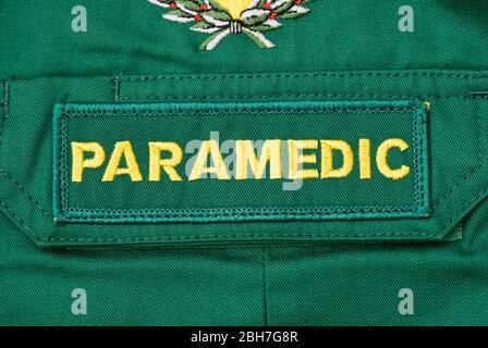 Vue rapprochée d'un badge britannique PARAMÉDIC cousue sur un maillot paramédic vert. Banque D'Images