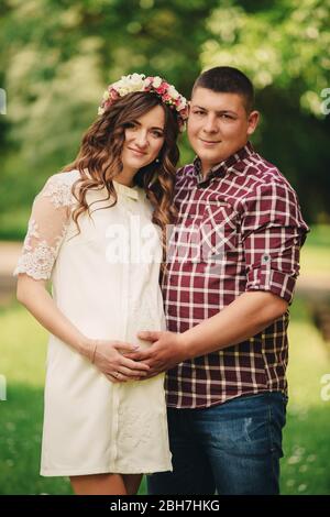 Jeune couple romantique de grossesse sur la nature dans le parc d'été. Femme enceinte attendant un bébé. Future maman et papa, famille. Mère, fête des pères. Banque D'Images