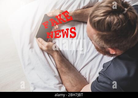 Fausses nouvelles infodemics pendant le concept de pandémie de Covid-19. Les mains de l'homme tenant le téléphone mobile lire les nouvelles mondiales ou le réseau social à la maison. Lire la dernière actualité Banque D'Images